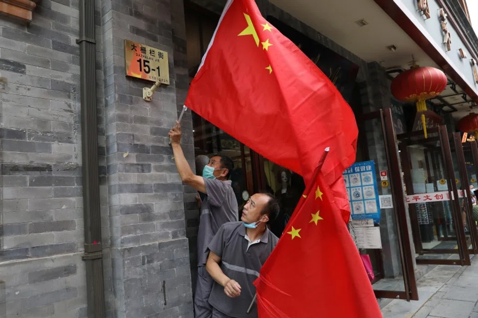 Workers set Chinese national flags on a shopping street ,ahead of a rehearsal for the celebrations to mark the 100th founding anniversary of the Communist Party of China, in Beijing, China, 26 June 2021. (Tingshu Wang/Reuters)