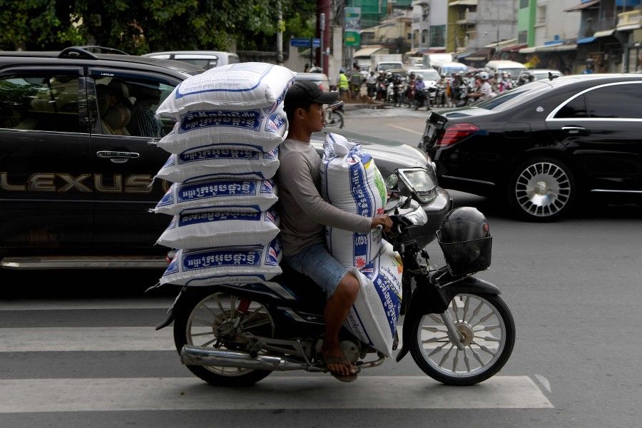 A man rides a scooter as he transports bags of rice in Phnom Penh on 25 September 2020. (Tang Chhin Sothy/AFP)