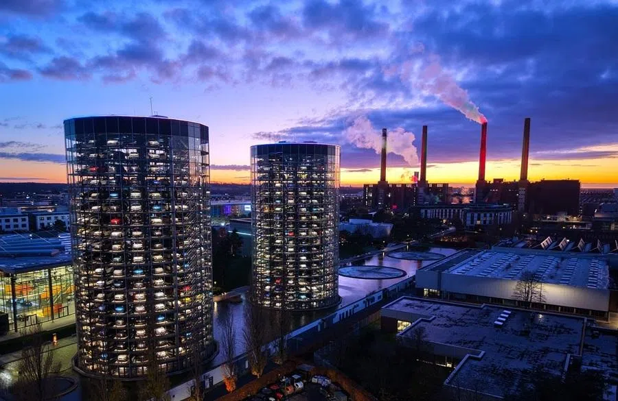 An aerial view shows the illuminated tower storage facility (left) and the power plant of German carmaker Volkswagen (VW) at the company’s headquarters in Wolfsburg, central Germany, at dusk on 21 November 2025.