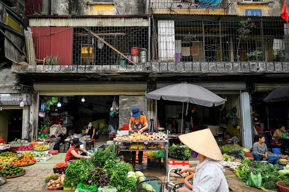 A vendor (centre) sells meat at her stall in front of a residential building in Hanoi, Vietnam on 31 March 2021. (Manan Vatsyayana/AFP)