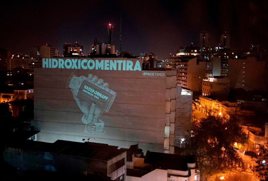 A projection on a building plays with the words "hydroxychloroquine" and "lie" as a protest against Brazilian President Jair Bolsonaro, a fervent advocate of the drug, during a tribute honouring the 100,000 victims who died of the Covid-19 coronavirus in Brazil, in Botafogo neighbourhood in Rio de Janeiro, Brazil, on 8 August 2020. (Mauro Pimentel/AFP)