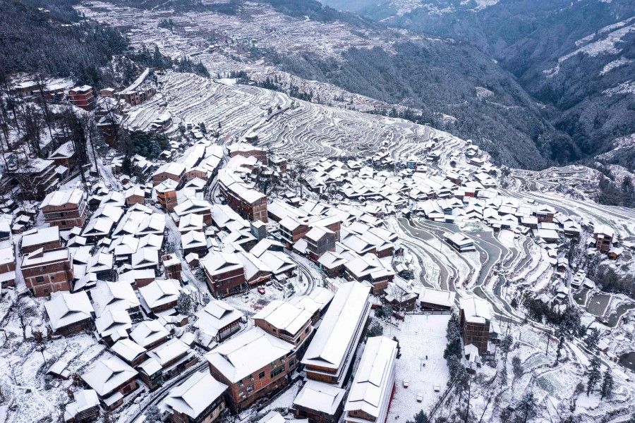 An aerial view shows snow-covered terraced fields and houses in Congjiang county, in China's southwestern Guizhou province on 22 January 2024. (AFP)