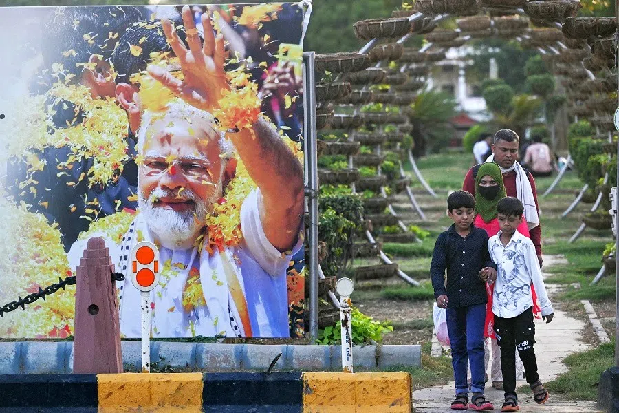 Pedestrians walk near a road next to a billboard displaying an image of India’s Bharatiya Janata Party (BJP) leader, Narendra Modi on the day of his oath-taking ceremony, in New Delhi, India, on 9 June 2024.