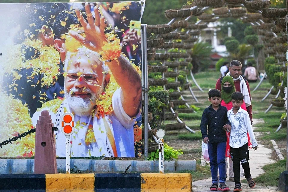 Pedestrians walk near a road next to a billboard displaying an image of India’s Bharatiya Janata Party (BJP) leader, Narendra Modi on the day of his oath-taking ceremony, in New Delhi, India, on 9 June 2024. (Arun Sankar/AFP)