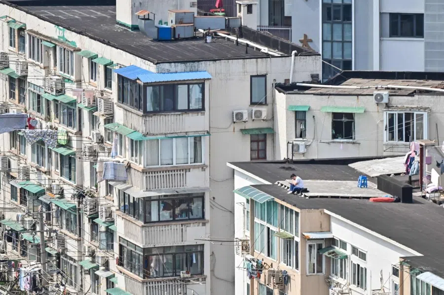 A resident (right) sits near the edge of a rooftop of a building during the second stage of the Covid-19 pandemic lockdown in the Jing'an district of Shanghai on 6 April 2022. (Hector Retamal/AFP)