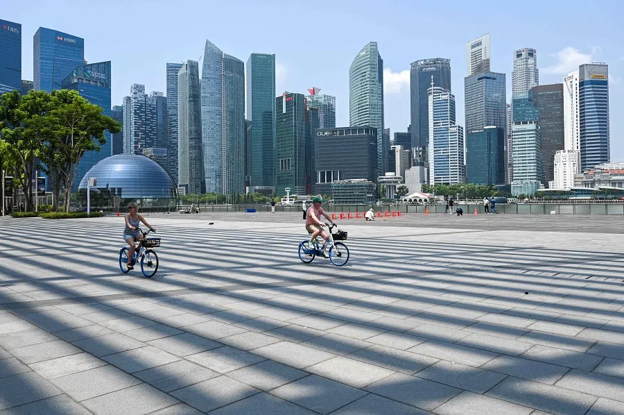 People cycle along the promenade at Marina Bay in Singapore on 13 October 2023. (Roslan Rahman/AFP)