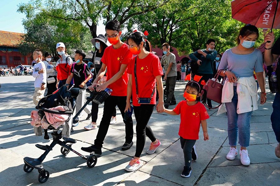 People wearing T-shirts with the design of the Chinese national flag walk outside the Forbidden City in Beijing, China, on 1 October 2021. (Jade Gao/AFP)