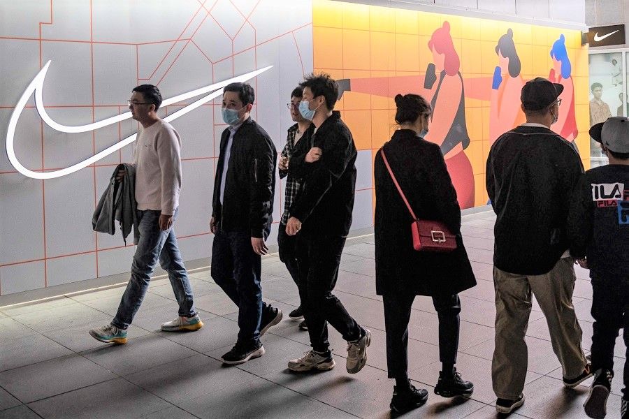 People walk past a Nike store in Beijing, China, on 5 April 2021. (Nicolas Asfouri/AFP)