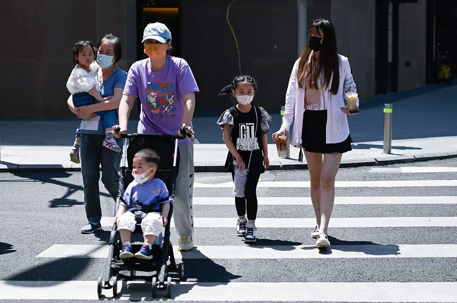 People cross a street in Beijing, China, on 1 June 2021. (Wang Zhao/AFP)