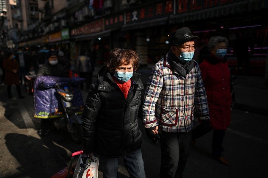 People walk along a street near a market in Wuhan, Hubei province, China, on 19 January 2021. (Hector Retamal/AFP)