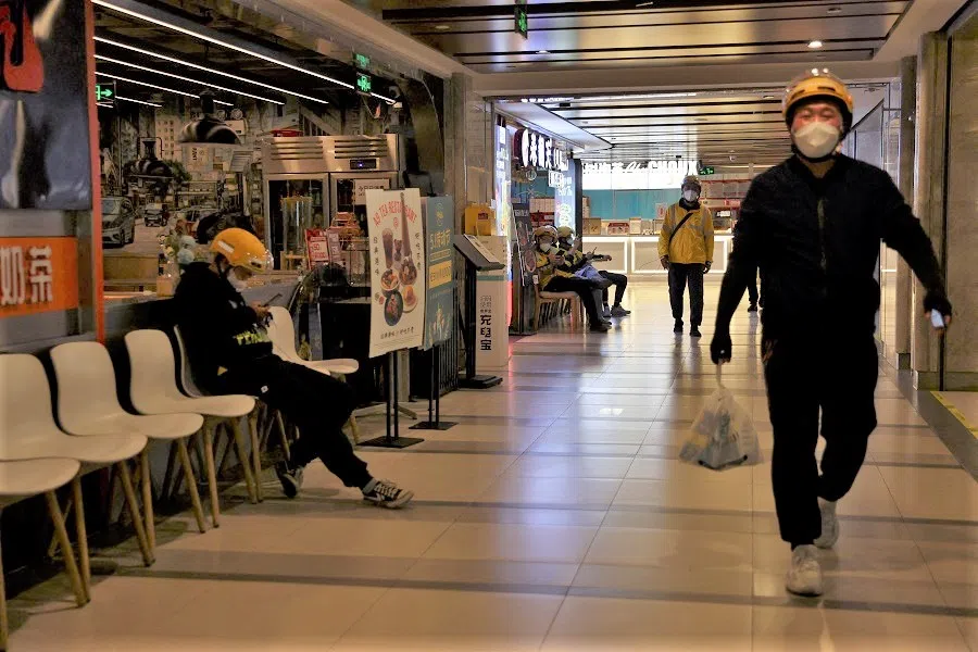 Couriers wait to pick up food delivery orders at a food court inside a shopping mall after the city banned dine-in services amid the Covid-19 outbreak in Beijing, China, 9 May 2022. (Tingshu Wang/Reuters)