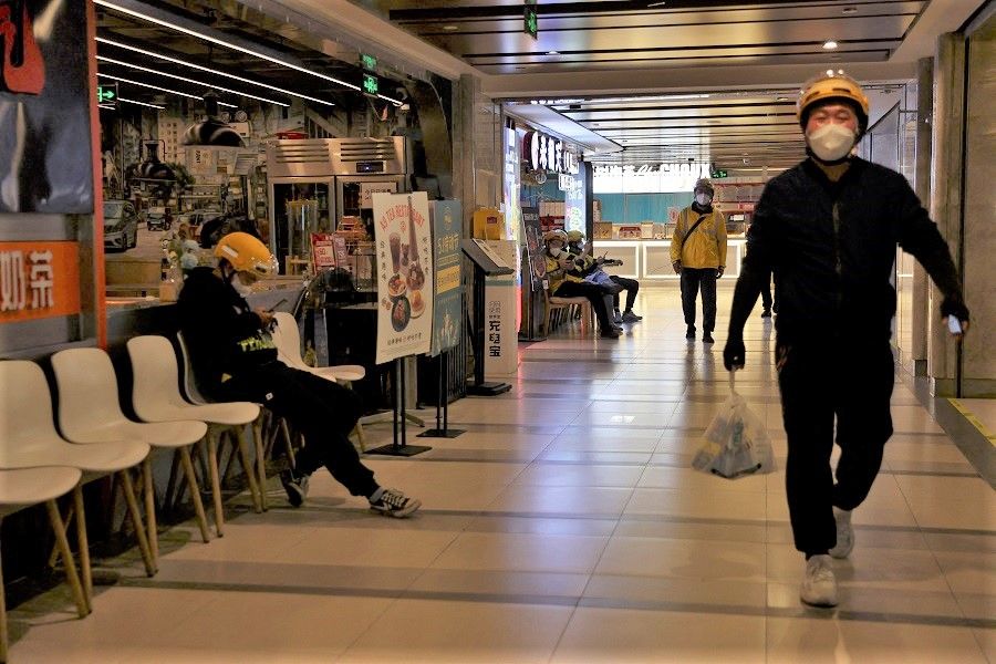 Couriers wait to pick up food delivery orders at a food court inside a shopping mall after the city banned dine-in services amid the Covid-19 outbreak in Beijing, China, 9 May 2022. (Tingshu Wang/Reuters)