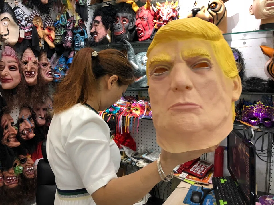 A vendor holding up a Donald Trump latex mask that she sells.