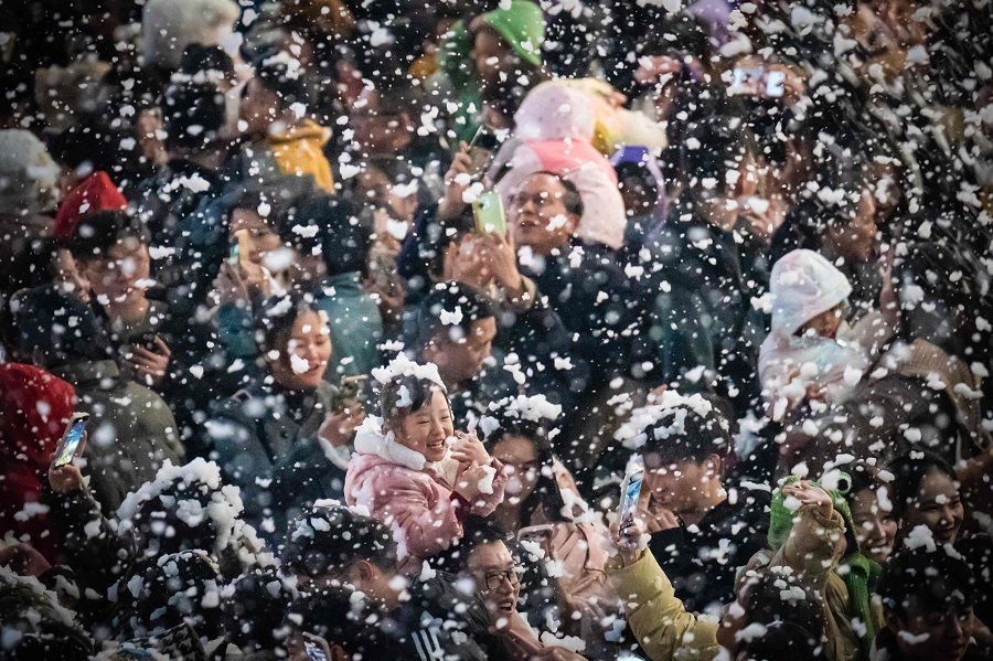 This photo taken on 24 December 2023 shows people visiting a business area with artificial snow in China's southwestern Chongqing municipality. (AFP)
