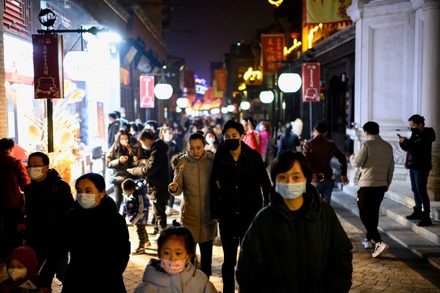 People wearing face masks walk at Qianmen Street in Beijing, China, on 11 February 2021. (Noel Celis/AFP)