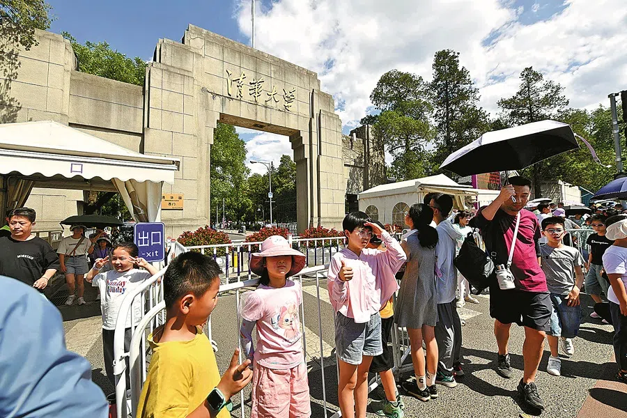 Tourists taking photos in front of a Tsinghua University gate in Beijing.