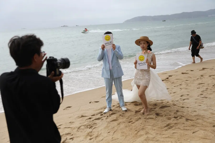 A couple poses for pictures during a wedding photoshoot session on Yalong Bay beach in Sanya, Hainan province, China, 26 November 2020. (Tingshu Wang/Reuters)