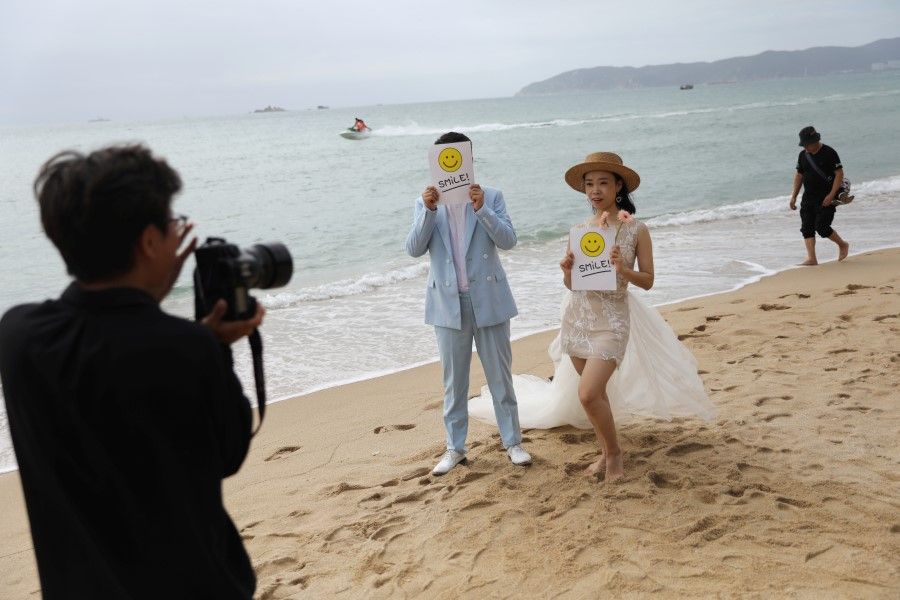 A couple poses for pictures during a wedding photoshoot session on Yalong Bay beach in Sanya, Hainan province, China, 26 November 2020. (Tingshu Wang/Reuters)