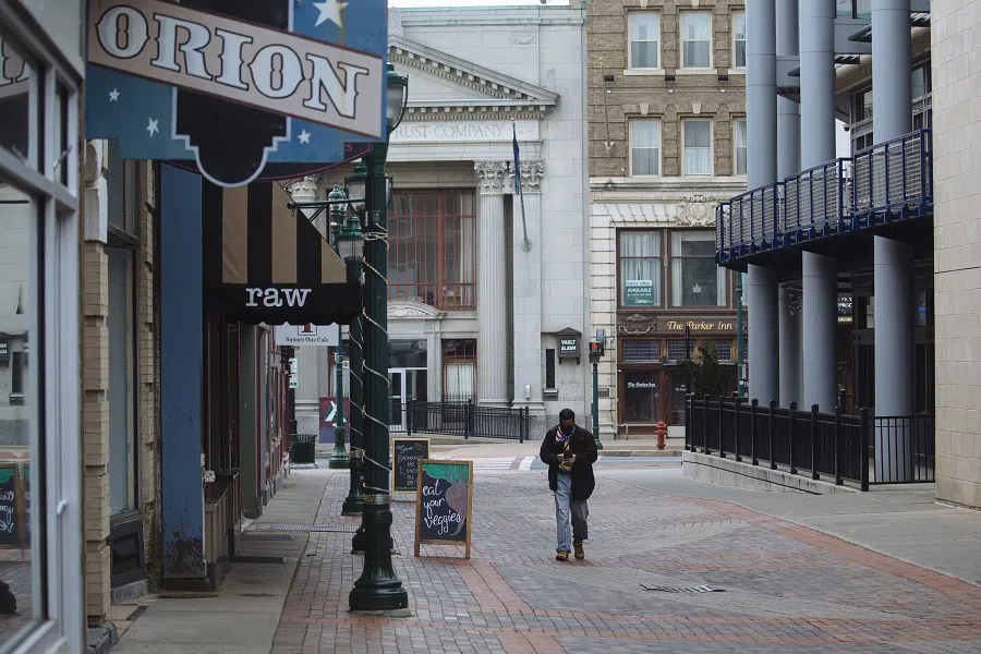 A pedestrian wearing a protective face mask walks down an empty pedestrian shopping area in Schenectady, New York, US, on 15 May 2020. (Angus Mordant/Bloomberg)