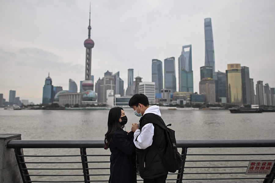 In this photo taken on 5 March 2021, a couple visits the promenade on the Bund along Huangpu River in Shanghai, China. (Hector Retamal/AFP)