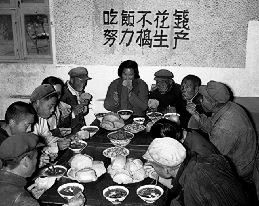 People eat at a people's communal canteen. The slogan on the wall says: Food is free, so just work hard on production. (Internet)