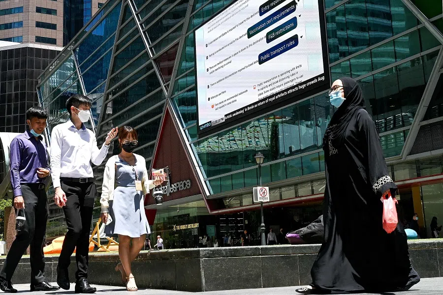 People walk out for a lunch break at Raffles Place financial district in Singapore on 22 August 2022. (Roslan Rahman/AFP)