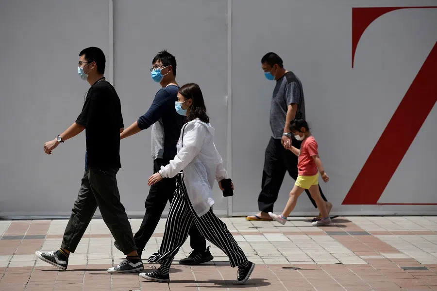 People wearing face masks amid the Covid-19 pandemic walk along a street in Beijing on 20 May 2020. (Wang Zhao/AFP)