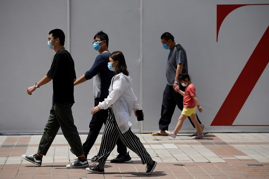 People wearing face masks amid the Covid-19 pandemic walk along a street in Beijing on 20 May 2020. (Wang Zhao/AFP)