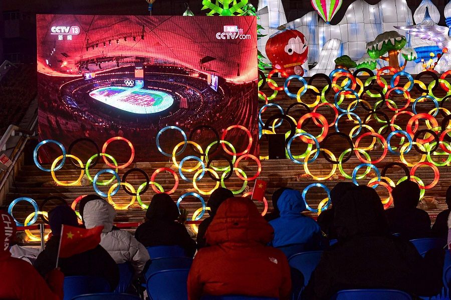 People watch a screen with live footage of the opening ceremony of the Beijing 2022 Winter Olympic Games at Shenyang Olympic Sports Centre in Shenyang, Liaoning province, China, on 4 February 2022. (AFP)