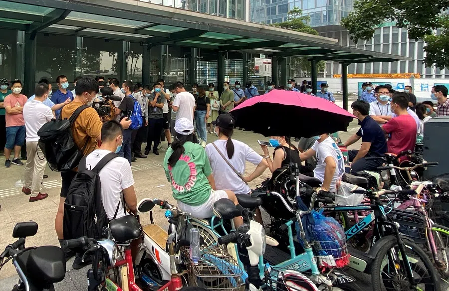 People gather to demand repayment of loans and financial products as security personnel guard outside Evergrande's headquarters in Shenzhen, China, 15 September 2021. (David Kirton/File Photo/Reuters)