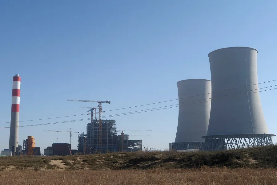 Chimney and cooling towers stand next to cranes at the construction site of Shenmu Shenxin power station, a coal-fired power plant, in Shenmu, Shaanxi province, China, on 20 November 2023. (Ella Cao/Reuters)