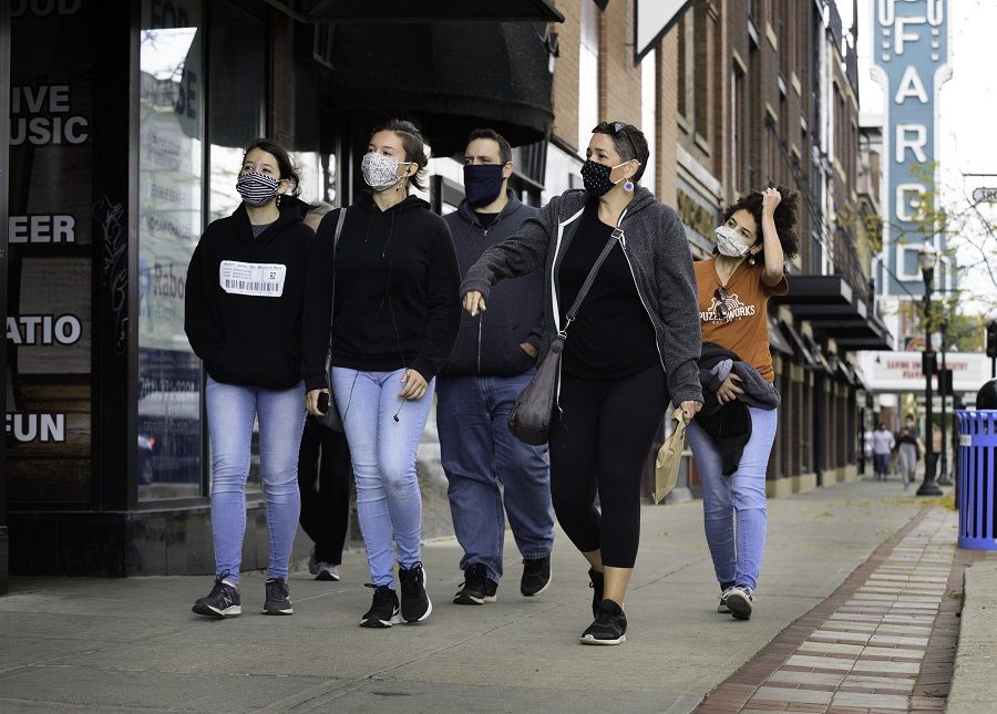 Pedestrians wearing protective masks pass in front of the Fargo Theatre in downtown Fargo, North Dakota, US, on 14 October 2020. (Dan Koeck/Bloomberg)