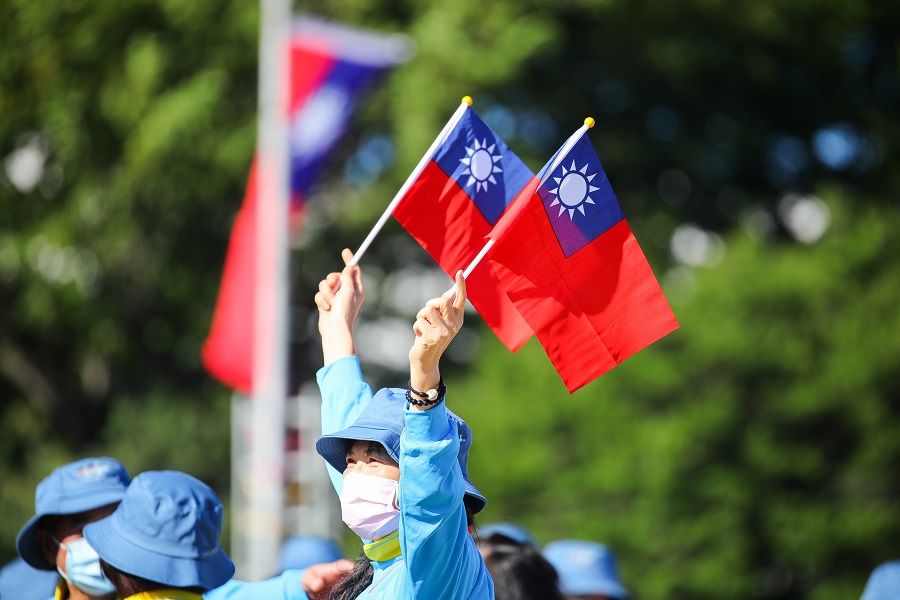 A woman holds Taiwanese flags in front of the Presidential Office before the Double Tenth Day celebration starts in Taipei, Taiwan, on 10 October 2021. (I-Hwa Cheng/Bloomberg)