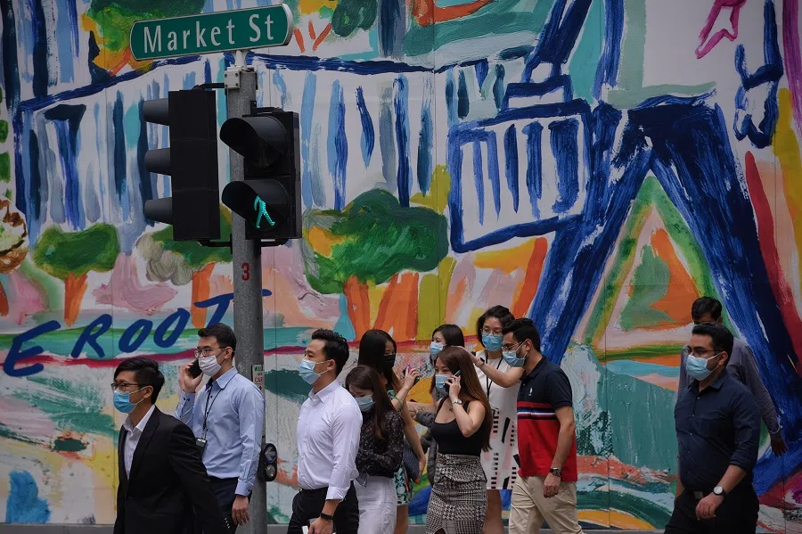 People wait to cross the road along Market Street during lunch hour in Singapore. (SPH Media)