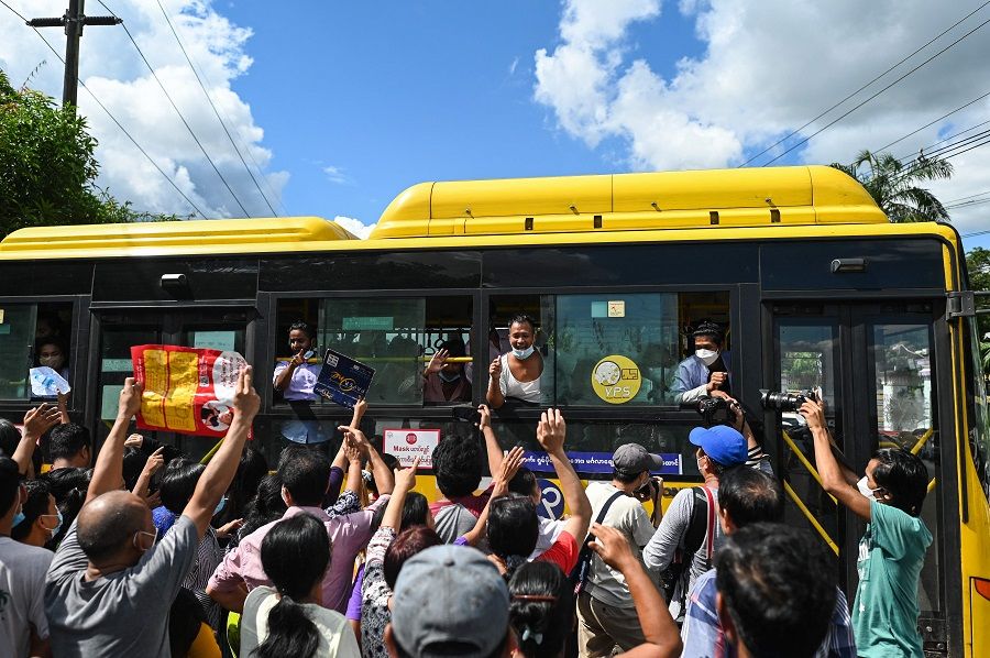 Detainees released from Insein Prison celebrate with the crowd from a bus in Yangon, Myanmar, on 19 October 2021, as authorities released thousands of people jailed for protesting against a February coup that ousted the civilian government. (STR/AFP)