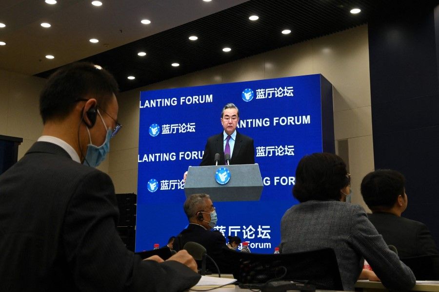 Chinese Foreign Minister Wang Yi is seen on a screen as he speaks at the Lanting Forum on China-US relations in Beijing on 22 February 2021. (Greg Baker/AFP)