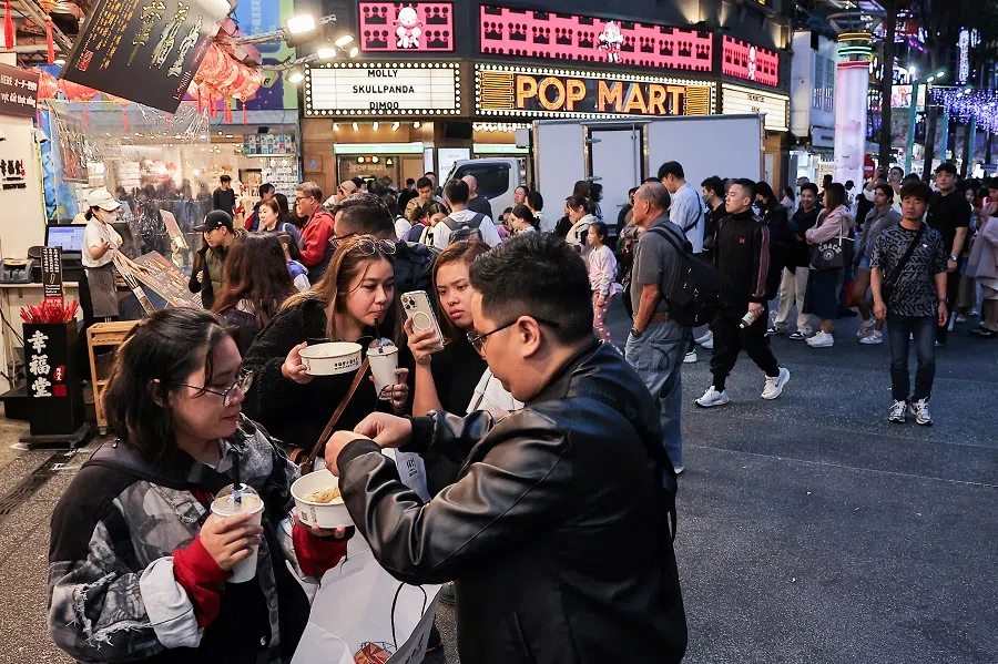 People take photos of their food at Ximending, a shopping district in Taipei, Taiwan, on 11 December 2024. (Ann Wang/Reuters)