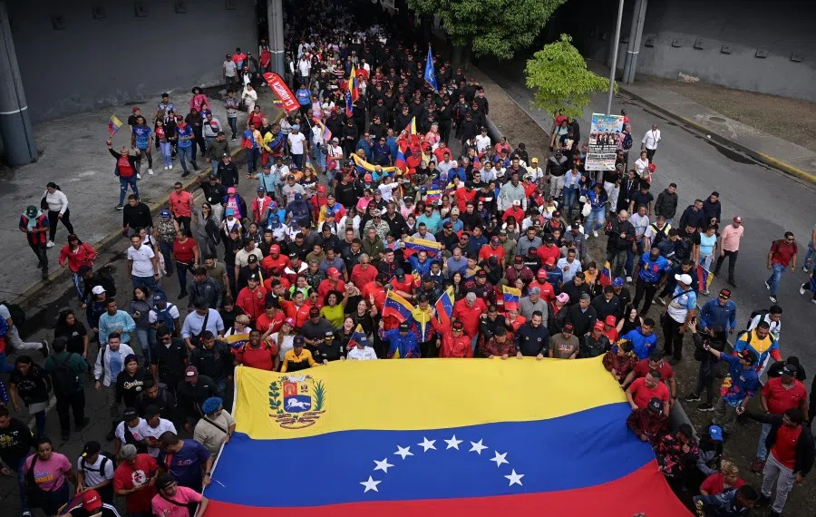 People display a large Venezuela national flag as they take part in a rally against a possible escalation of US actions toward the country, in Caracas, Venezuela, on 25 November 2025. (Gaby Oraa/Reuters)