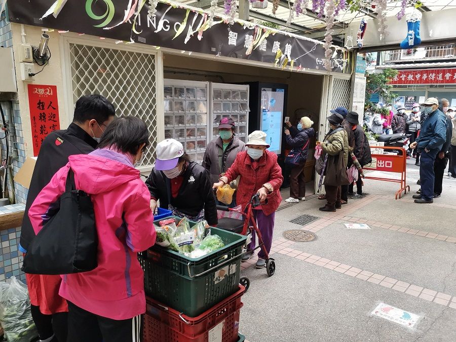 Elderly queue up to receive vegetables provided by the South Airport Joyous Living Centre.