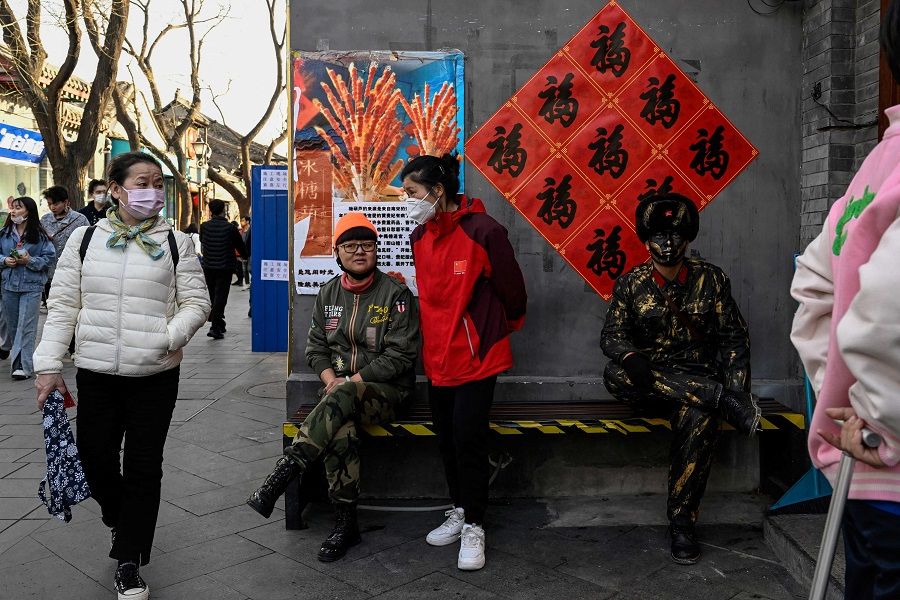 People rest on a bench at the Nanluoguxiang alley in Beijing, China, on 3 March 2023. (Jade Gao/AFP)