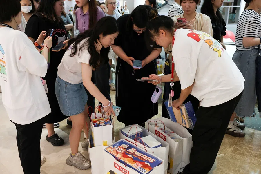 Customers receive Pop Mart products, ordered online, outside Pop Mart’s flagship store in Shanghai, China, on 13 June 2025. (Go Nakamura/Reuters)