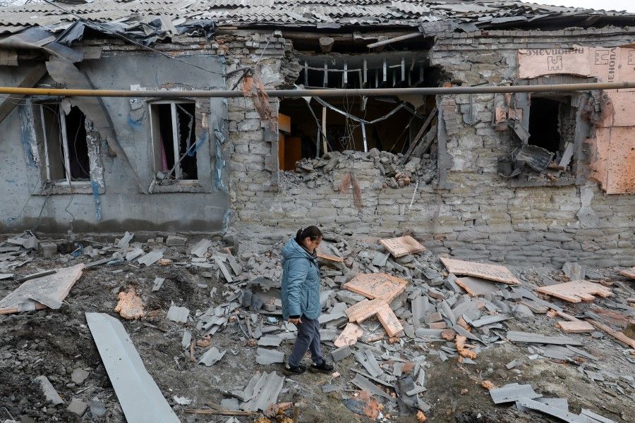 A woman walks past a house destroyed in recent shelling in the course of the Russia-Ukraine conflict in Donetsk, Russia-controlled Ukraine, 12 March 2023. (Alexander Ermochenko/Reuters)