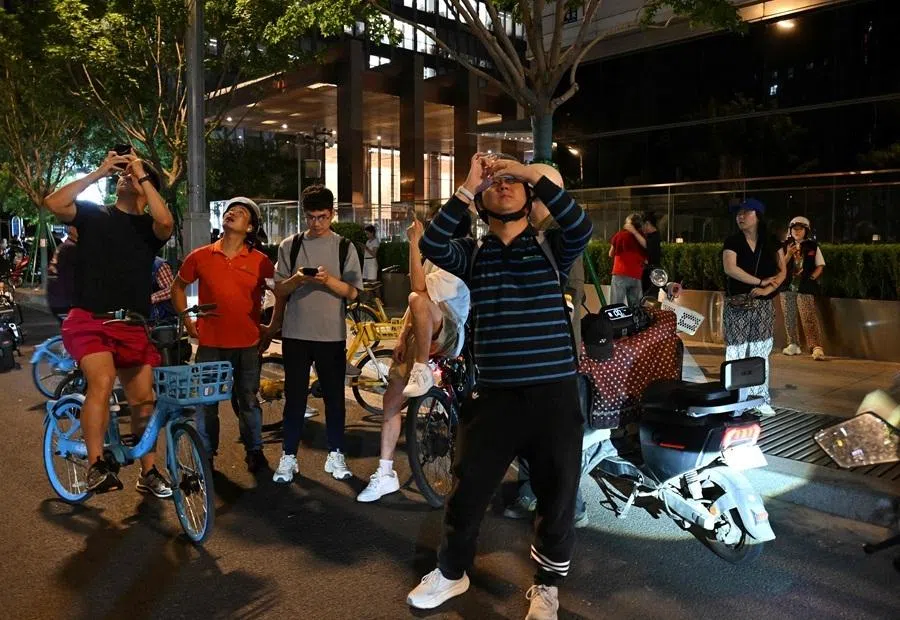 People take photographs of the CITIC Tower in Beijing on 26 June 2026, after an eyewitness reported plane debris at the base of Beijing's tallest building.