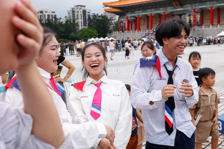 Students wearing the Taiwan flag on their shoulders laugh at an army recruitment event in Taipei, Taiwan, on 1 July 2023. (Ann Wang/Reuters)