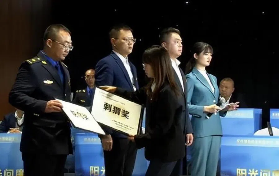 An awardee from Chuanshan, Suining, receiving his “award” whilst wearing a vacant expression. (Screen grab from video)