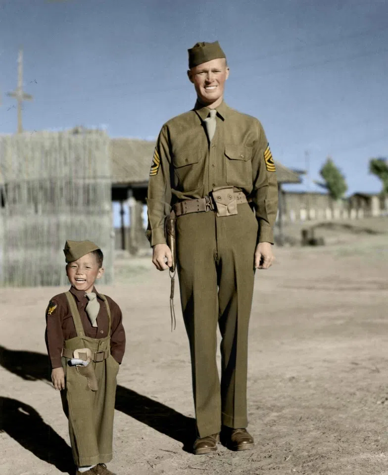 Everyone loved the cute and mischievous Little Tiger Joe, an orphan taken in by the 14th Air Force in Kunming. In this photo, he wears a little Flying Tigers uniform and hat, complete with a tie and dungarees, as well as a toy gun at his waist, imitating the pose of 1st Sgt. Robert Duerson beside him.