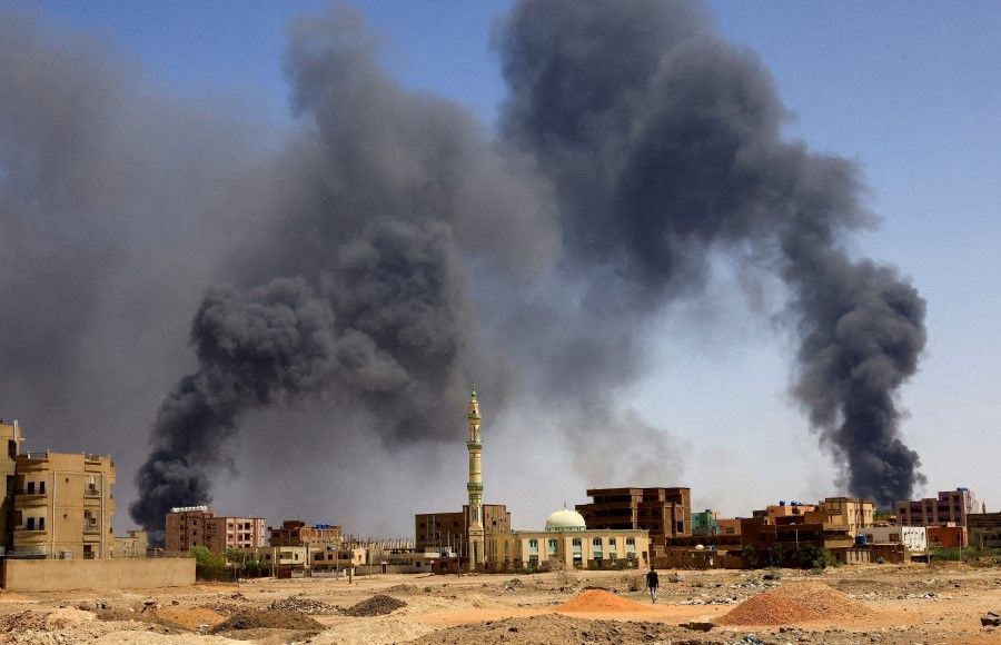 A man walks while smoke rises above buildings after aerial bombardment, during clashes between the paramilitary Rapid Support Forces and the army in Khartoum North, Sudan, 1 May 2023. (Mohamed Nureldin Abdallah/Reuters)