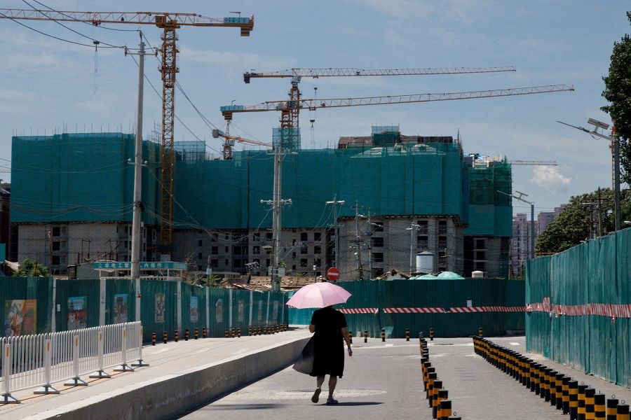 A woman walks near a construction site of apartment buildings in Beijing, China, on 15 July 2022. (Thomas Peter/File Photo/Reuters)