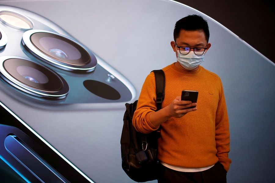 A man wears a face mask while waiting at an Apple Store before Apple's new iPhone 12 goes on sale in Shanghai, China on 23 October 2020. (Aly Song/File Photo/Reuters)