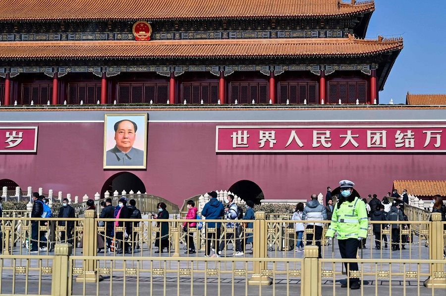 People are seen next to a portrait of late communist leader Mao Zedong on Tiananmen, in Beijing, China, on 3 March 2022. (Hector Retamal/AFP)